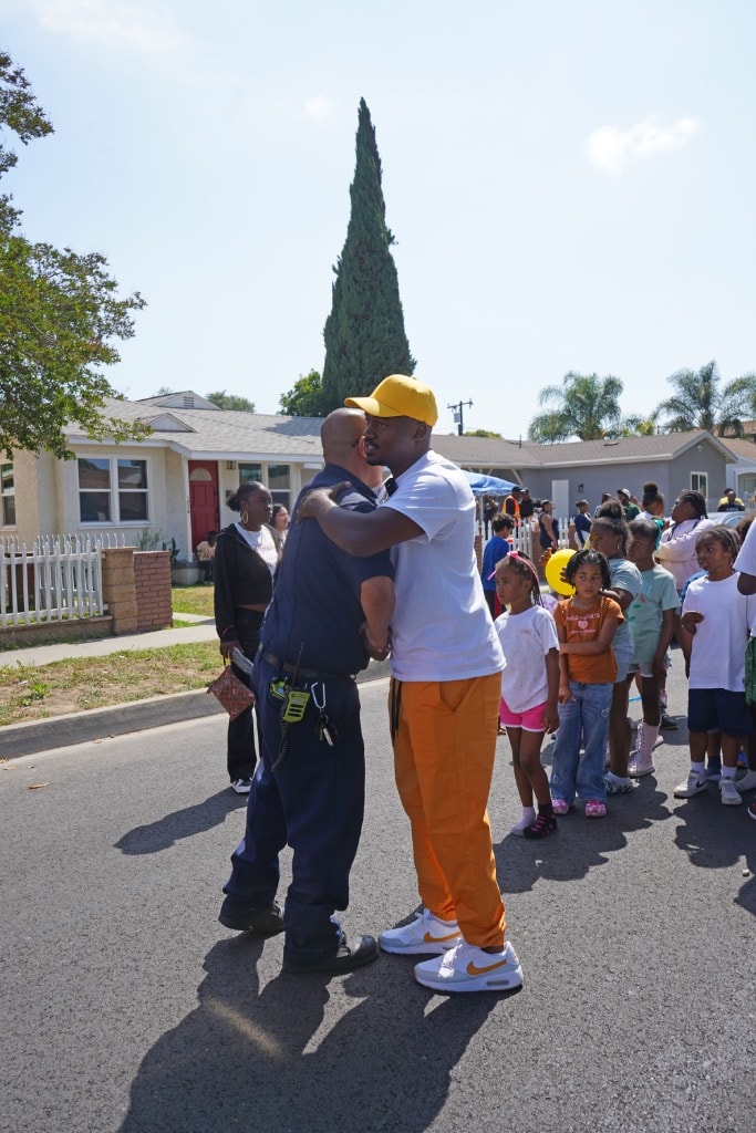 Dee Stallworth in yellow cap and orange pants greeting a firefighter at a community event