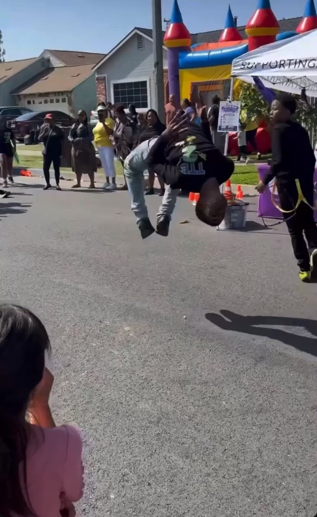 Youth performing a backflip on the street at a DSE community event with bounce house in background